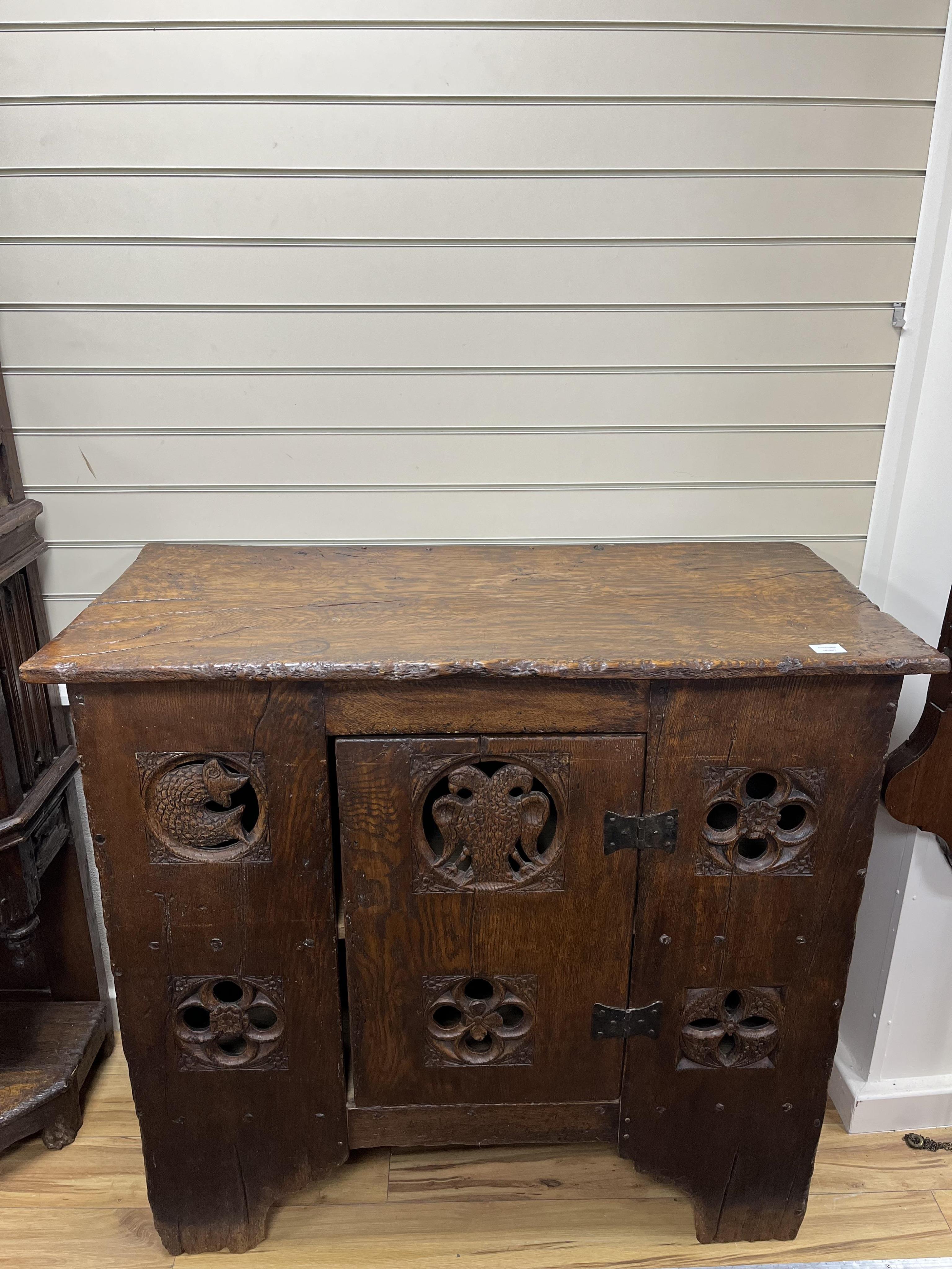 A boarded oak aumbry, in 16th century Tudor style, pierced and carved with armorial crests to the roundels, width 118cm, depth 55cm, height 114cm. Condition - fair to good, Provenance - made for Brede Place, Brede, Rye,